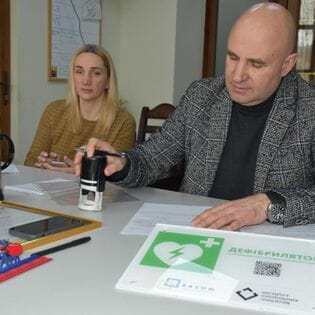 The head of the Slavsko settlement signs the act of receiving a defibrillator for the Slavsko Municipal Hospital from a public organization  