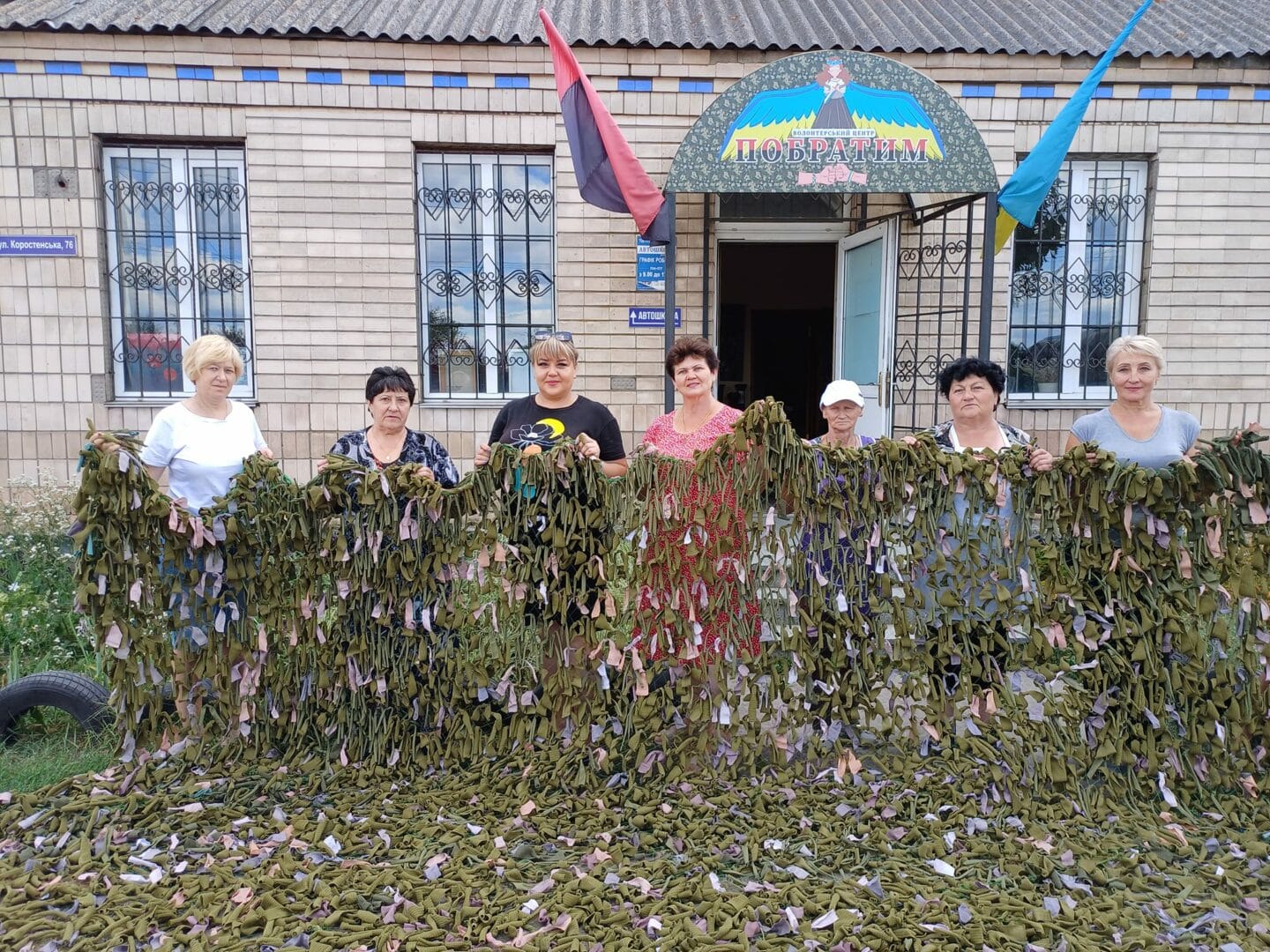 Community volunteers with a camouflage net for the Armed Forces