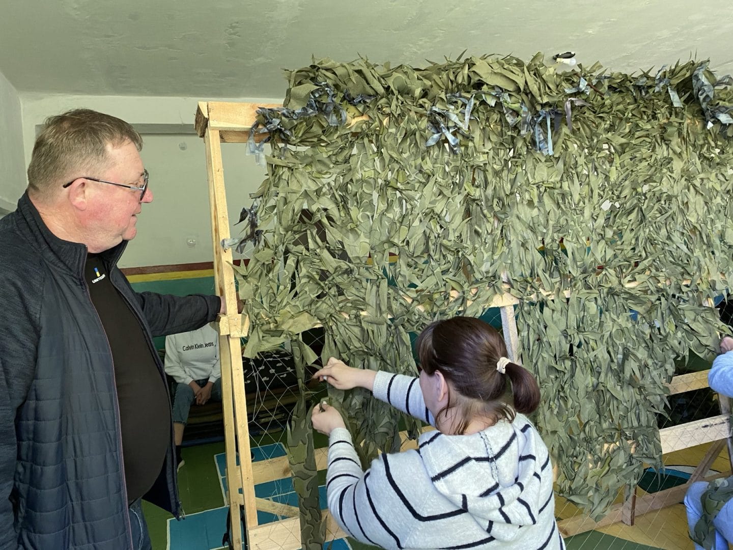 Teachers weaving camouflage nets