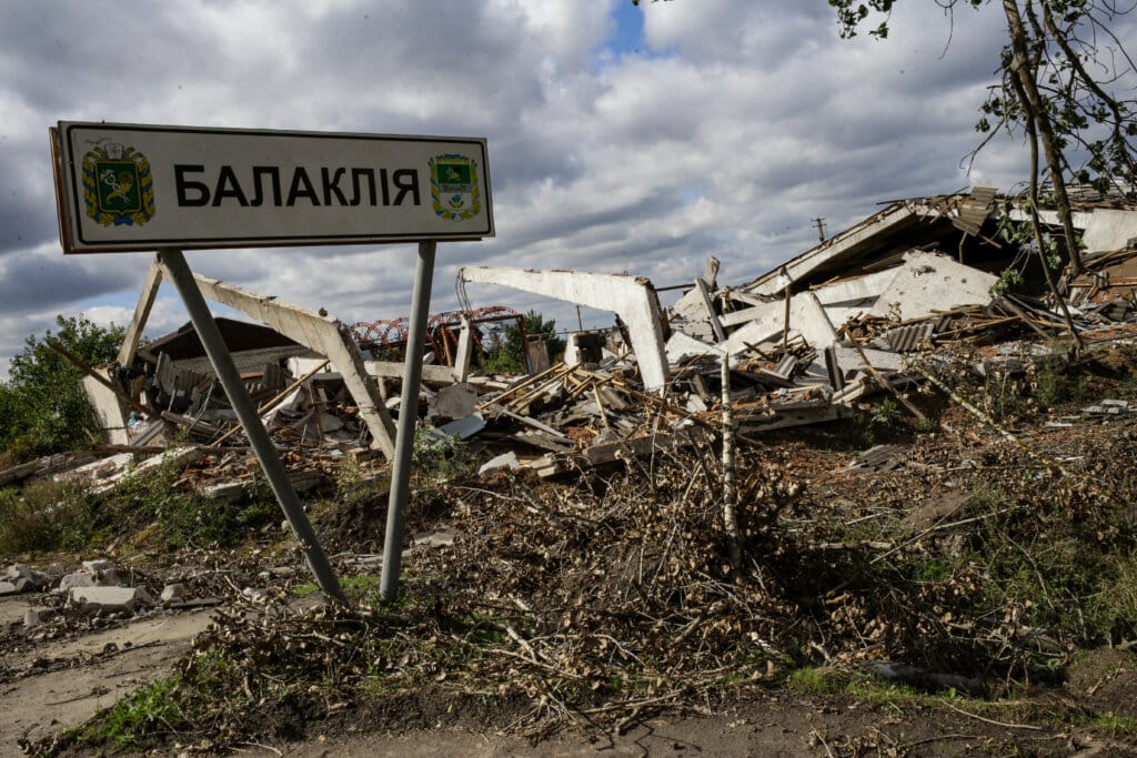 Road sign on the background of destroyed buildings in Balaklia