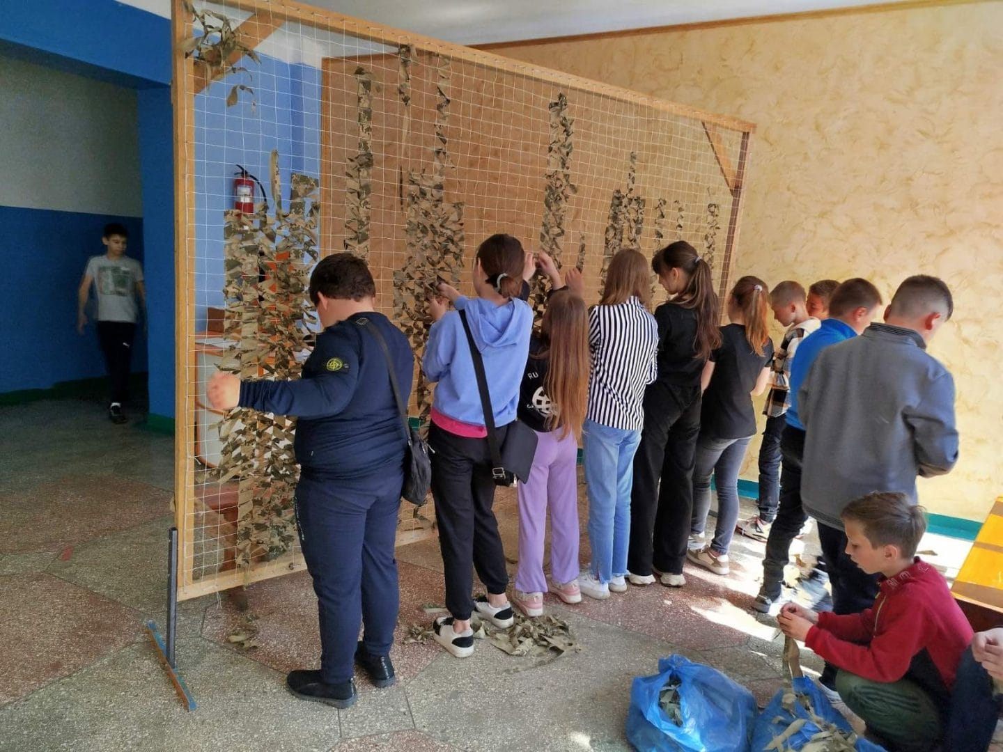 Pupils of the base institution “Skorokhodove Lyceum” weaving a camouflage net for the military during breaks