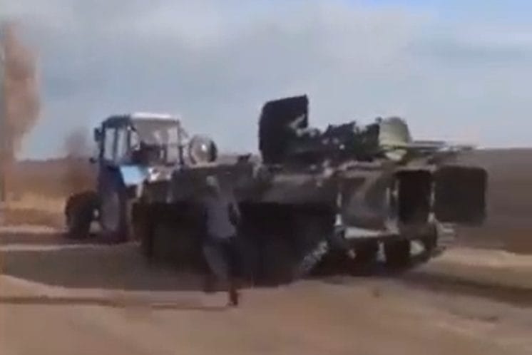 Community residents using a tractor to pull a tank stolen from the Russian occupiers 